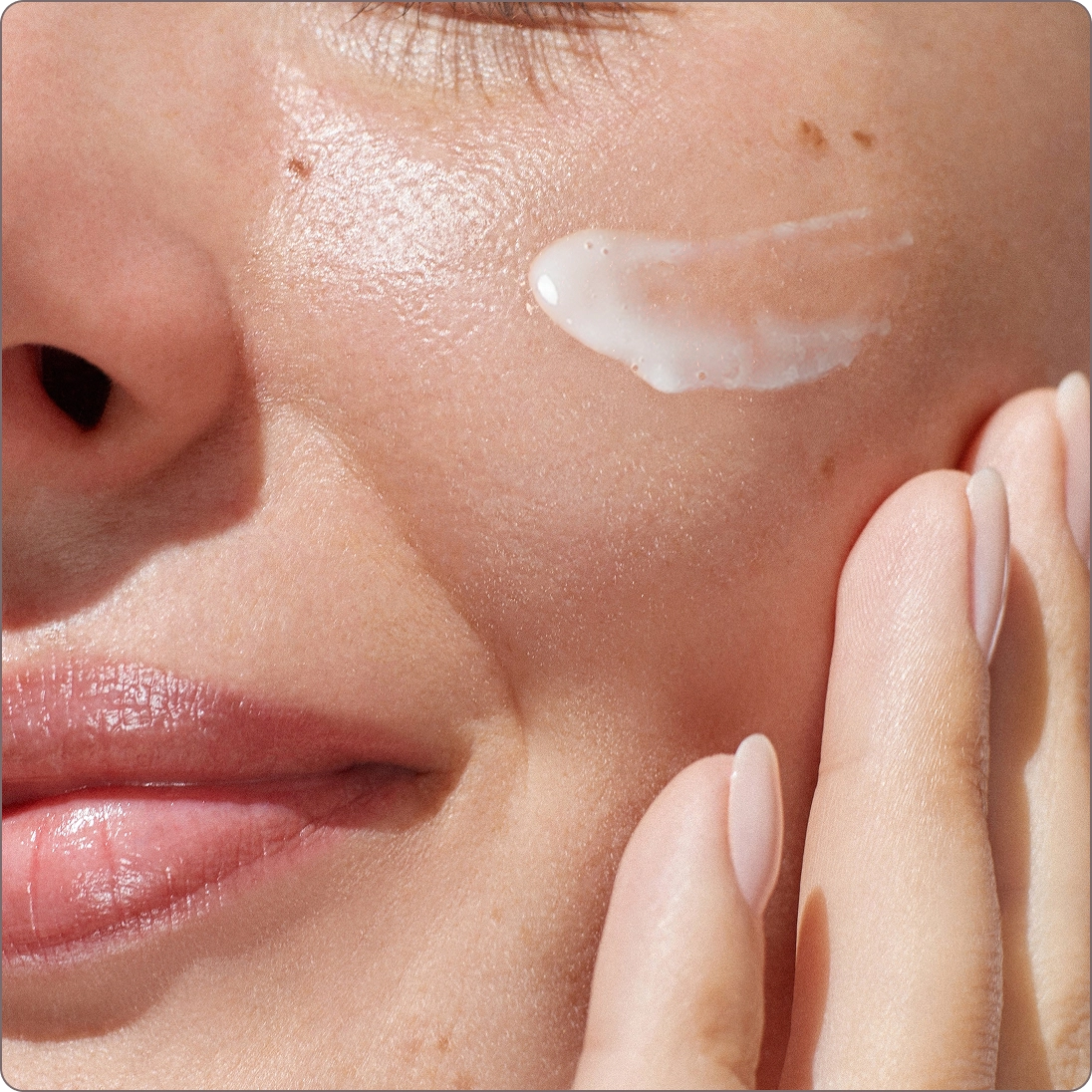 Close-up of woman applying serum with visible glow.