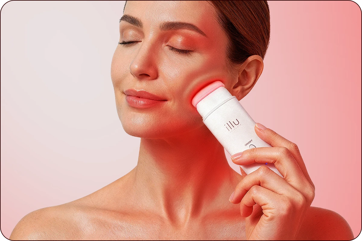 Woman using Illu red light therapy device on cheek with visible skin glow.