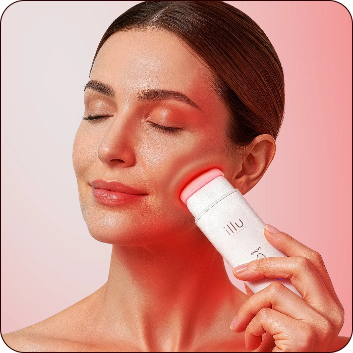 Woman using Illu red light therapy device on cheek with visible skin glow.